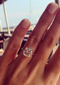 a woman's hand with a ring on it and a boat in the background