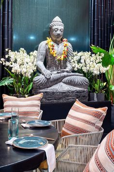 a buddha statue sitting on top of a table next to a vase filled with flowers