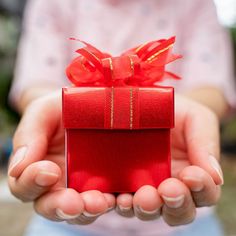 a person holding a small red box with a bow on it