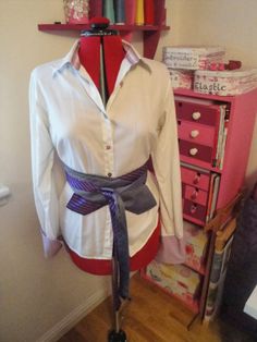 a mannequin wearing a white shirt and purple ribbon tied around it's waist