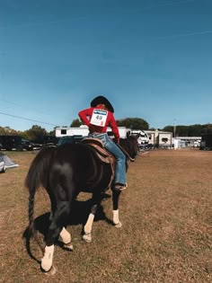 a man riding on the back of a brown horse in a field next to a trailer