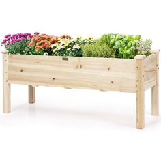 a wooden planter filled with lots of different types of flowers and plants in it