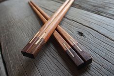 two wooden chopsticks laying on top of a wooden table next to each other