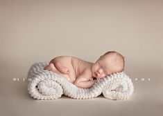 a newborn baby is wrapped in a white blanket and sleeping on it's side