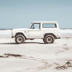 a white truck parked on top of a sandy beach