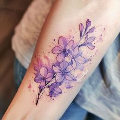 a woman's arm with purple flowers and watercolors on the left side