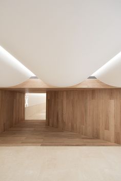 an empty room with wooden floors and white walls, is lit by recessed lights