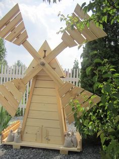 a wooden windmill sitting in the middle of a garden