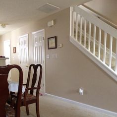 a dining room table and chairs in front of an open stair case with white railings