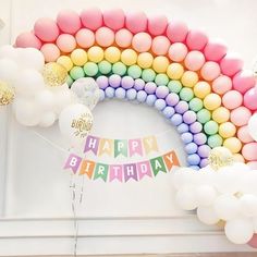 a rainbow birthday decoration with balloons and streamers