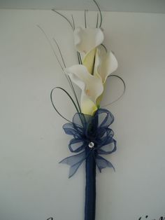 two white calla lilies are attached to a blue ribbon with the word congratulations written on it