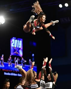 a cheerleader is in the air above her team