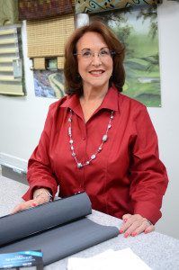 a woman is sitting at a table with some fabric on it and smiling for the camera