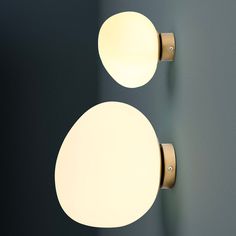 two round lights are on the wall next to each other, one light is dim