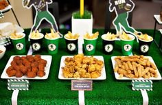 a table topped with lots of food and plates filled with fried chicken on top of green trays