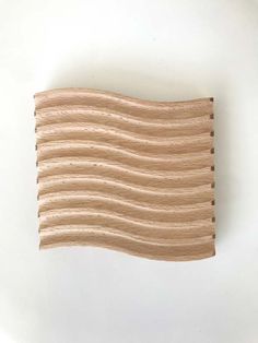 a piece of wood that looks like wavy lines on a white surface with holes in the middle