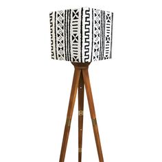 a wooden tripod floor lamp with a black and white lampshade on it