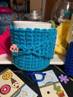 there is a cup holder made out of crocheted material and some buttons on it