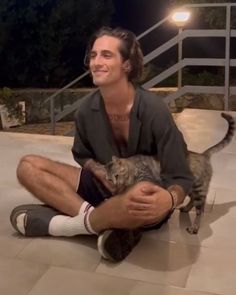 a man sitting on the ground holding a cat