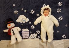 a baby in a snowman costume laying next to two stuffed animals