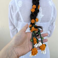 a woman is holding some crocheted flowers in her left hand and wearing a white shirt