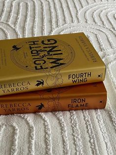 three books sitting on top of a bed in front of a white bedspread