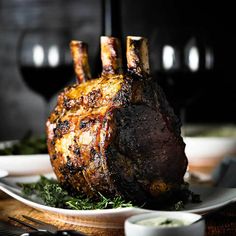 a piece of meat sitting on top of a white plate next to a glass of wine