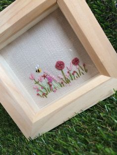 an embroidered picture frame with flowers in the grass