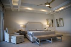 a bedroom with a bed, chair and ceiling fan in the middle of the room