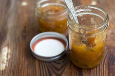 two jars filled with food sitting on top of a wooden table next to a spoon