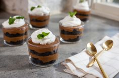 small desserts with whipped cream and chocolate pudding in glass containers on a counter top