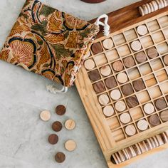 a wooden board game set on a table with coins and a bag next to it