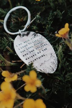 a keychain with a poem on it sitting in the grass next to yellow flowers