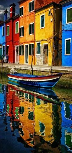 a boat floating on top of a body of water next to colorful buildings in the background