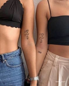 two women with matching tattoos on their arms and stomachs, both wearing crop tops