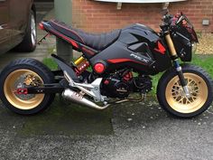 a black and red motorcycle parked on the side of a road next to a brick building