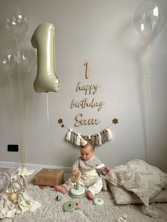 a baby is sitting on the floor in front of balloons