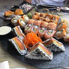 an assortment of sushi on a platter with dipping sauce