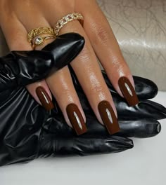 a woman's hand with brown and white nail polish on her nails, wearing black gloves