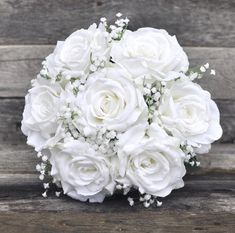 the bridal bouquet is white with baby's breath in it on a wooden surface