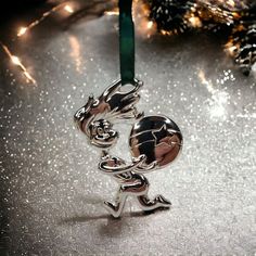 a silver ornament with a green ribbon hanging from it's side on a table