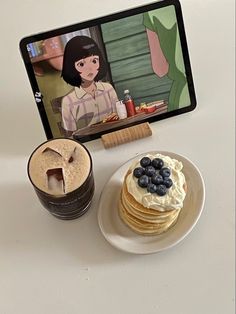 there is a plate with pancakes and a cup of coffee on the table next to it