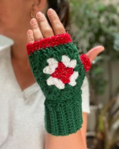 a woman is holding her hand up to the camera while wearing a green and white knitted mitt