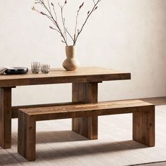 a wooden table with two benches next to it and a vase filled with flowers on top