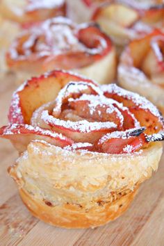 several pastries with powdered sugar on them are sitting on a wooden table next to each other