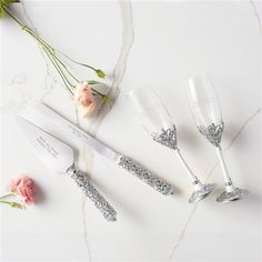 three wine glasses and a knife on a marble surface with flowers in the background,