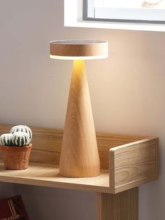 a wooden table with a lamp on it next to a potted cactus