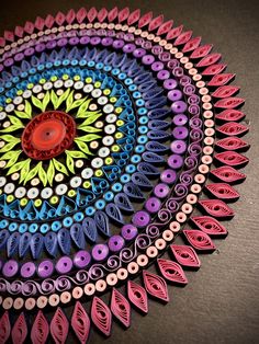 a colorful paper doily is shown on a black surface with circles and leaves in the center