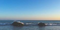 two rocks in the water with waves coming up on them and one rock sticking out of the water