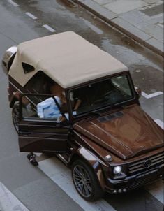 a brown car with a beige roof and two people in it